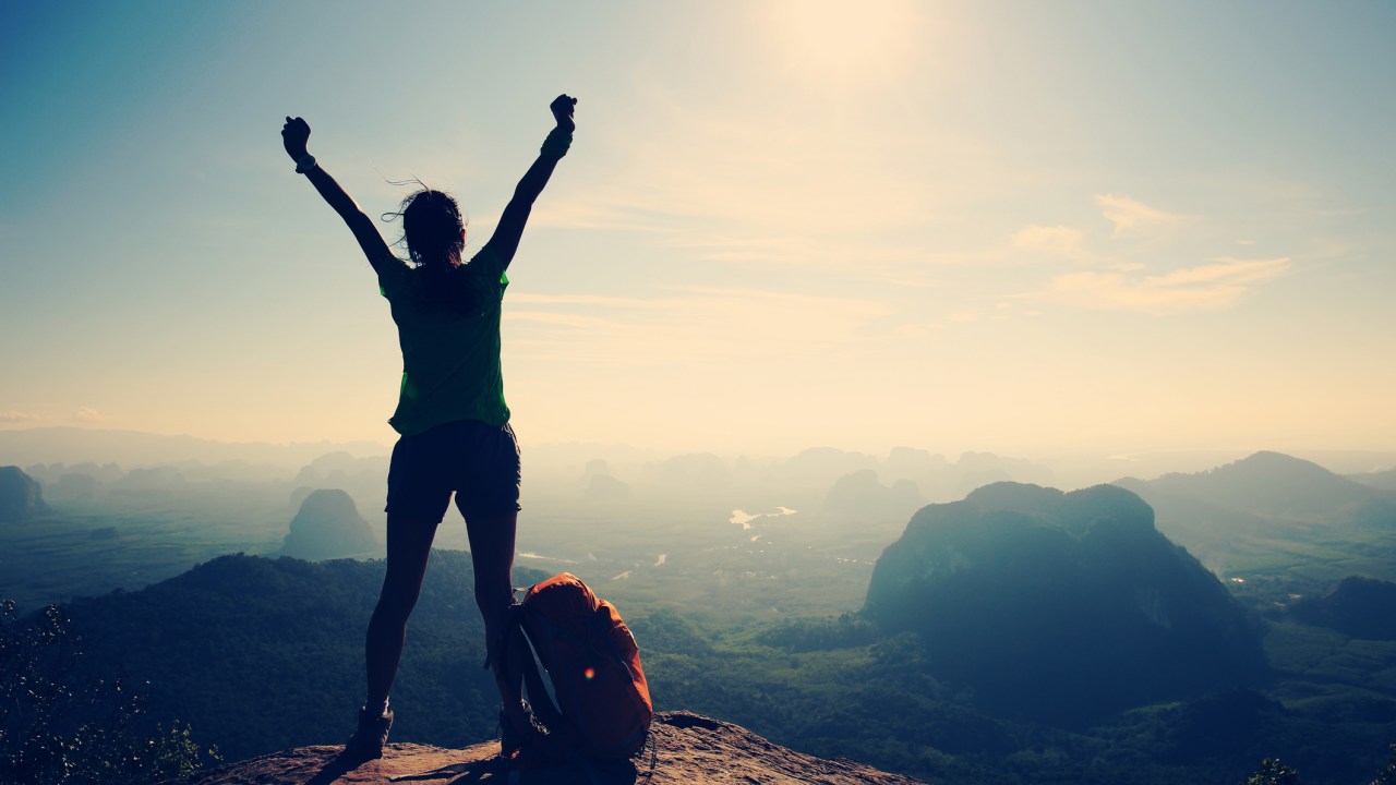 Mulher feliz no alto de montanha com mochila