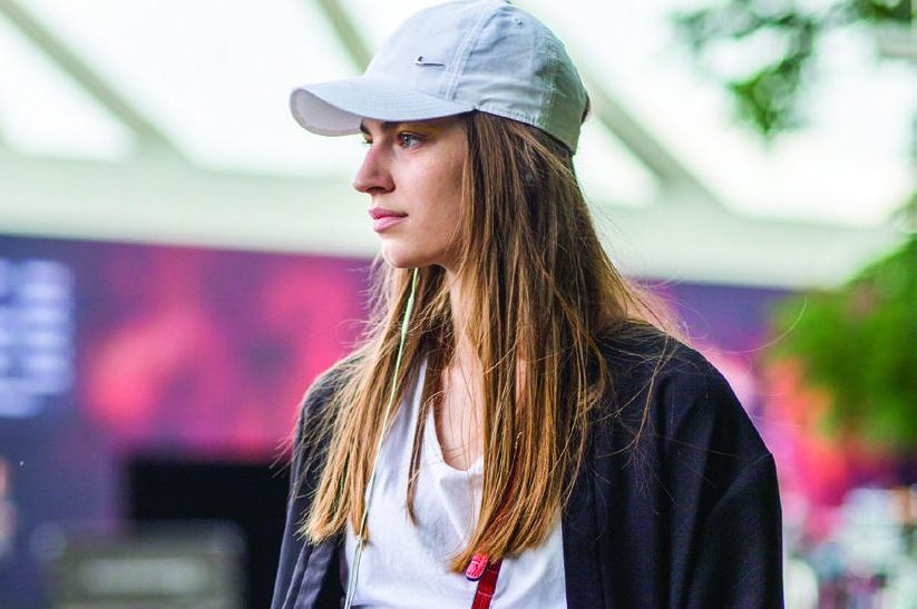Modelo andando na rua com roupa esportiva e boné