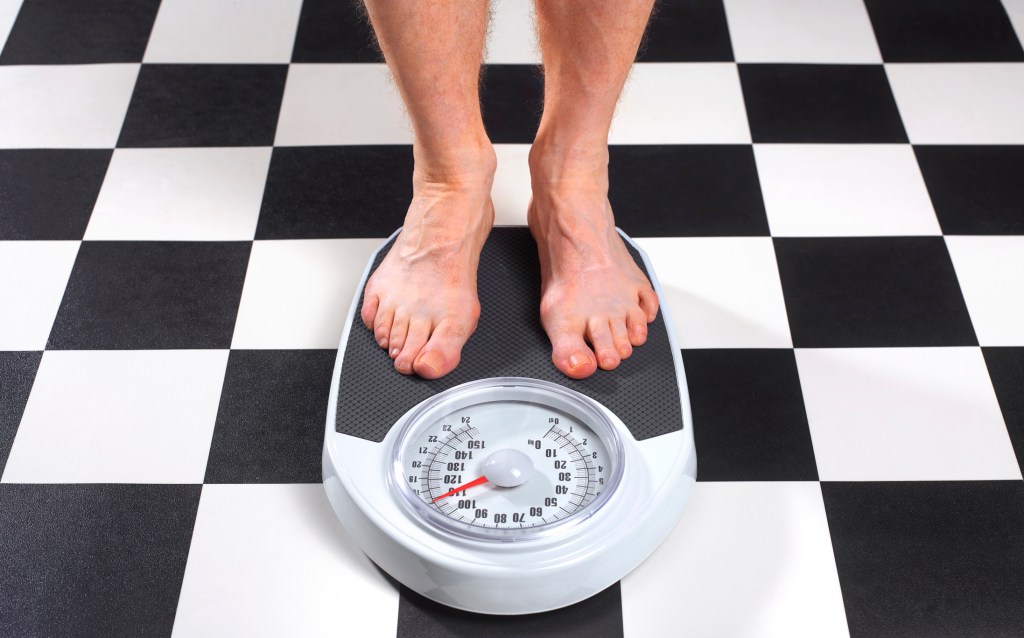 Overweight Man Standing on Bathroom Scales Overweight Man Standing on Bathroom Scales