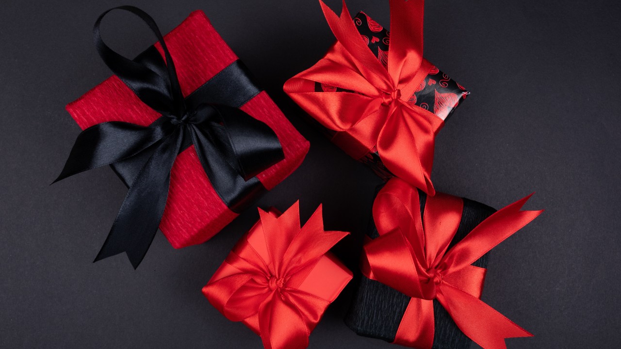 3 caixas de presentes de natal, as caixas sao pretas e a têm uma fita vermelha em volta