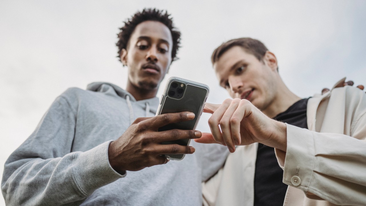 dois homens usando celular com a cabeça abaixada
