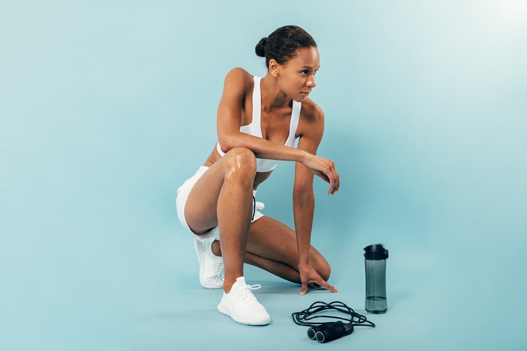 Woman Looking Away While Sitting Against Blue Background treino exercicio emom
