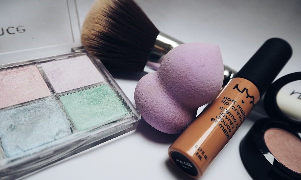 Paleta de sombras com corretivo da marca Nyx e pincel de maquiagem ao lado