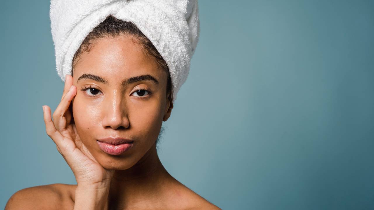 mulher com rosto limpo e toalha na cabeça