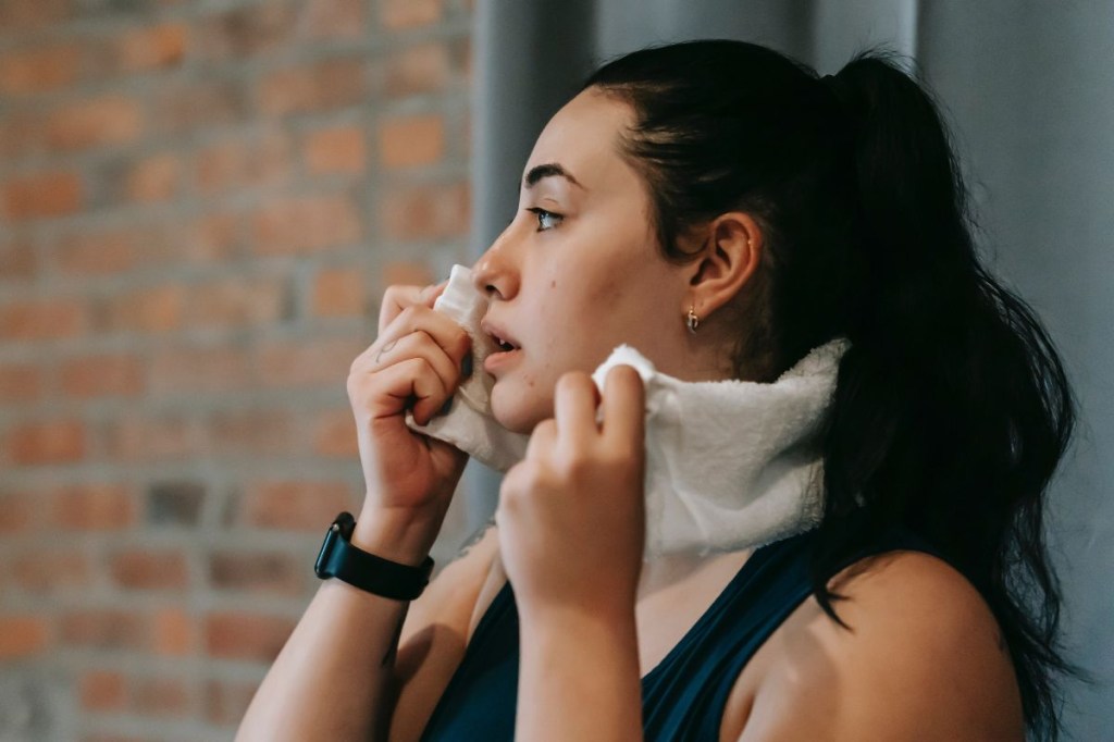intensidade-exercícios Mulher secando o rosto após treino