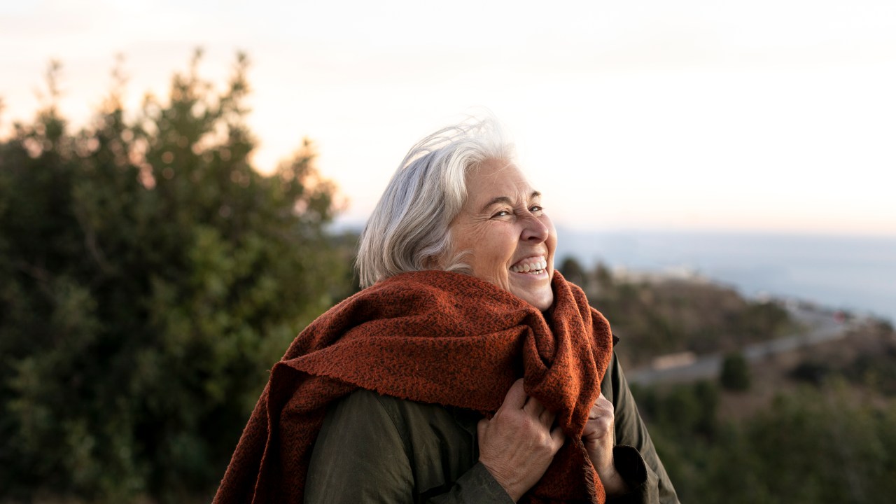 mulher idosa sorrindo em um lugar montanhoso