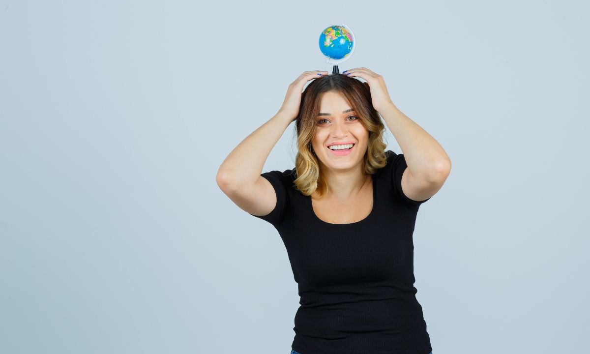 Mulher vestindo camiseta preta e segurando um globo terrestre na cabeça