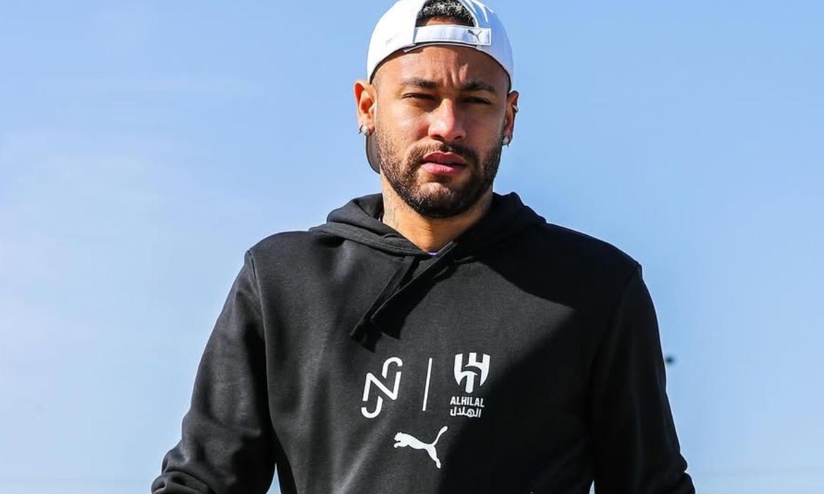 Neymar utilizando um boné branco e vestindo um moletom com capuz preto